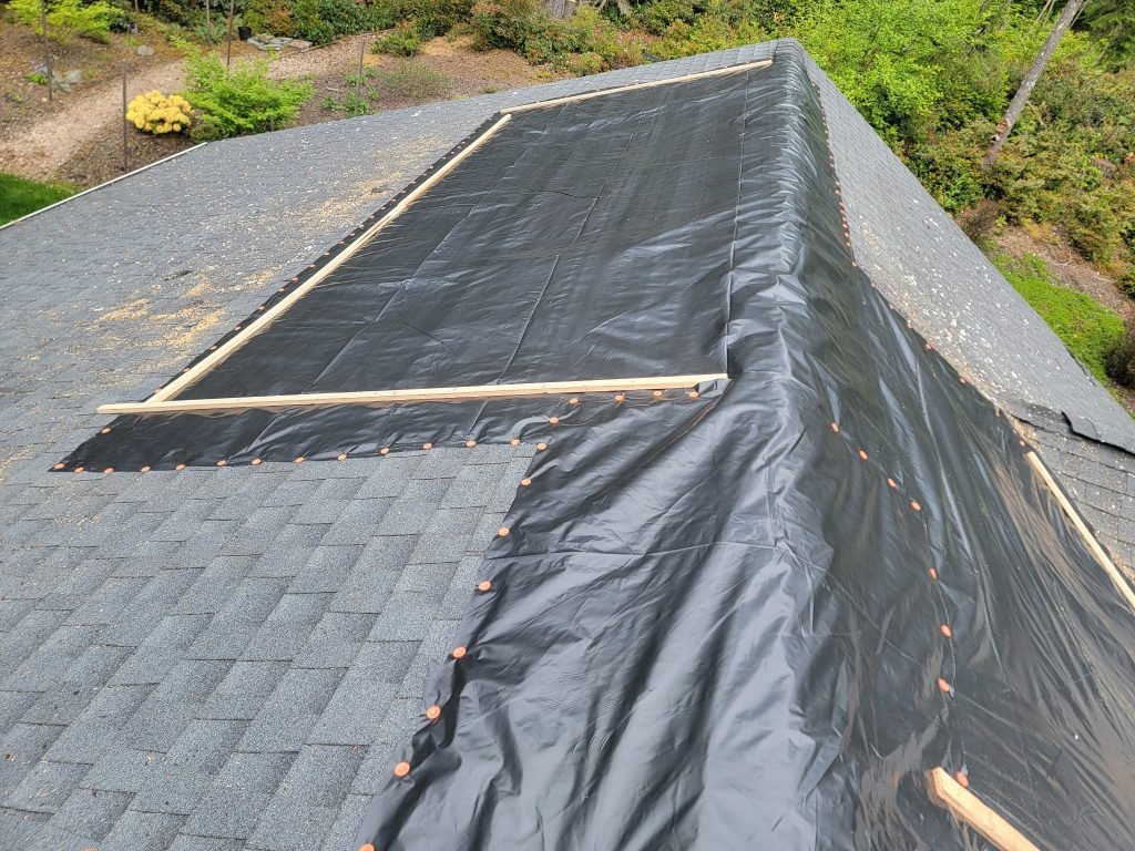 Roof underlayment and tarps secured with nails on residential roof repair