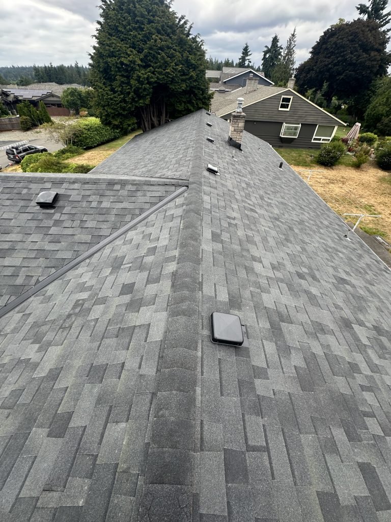 Gray asphalt shingle roof with ridge vents and chimney vent