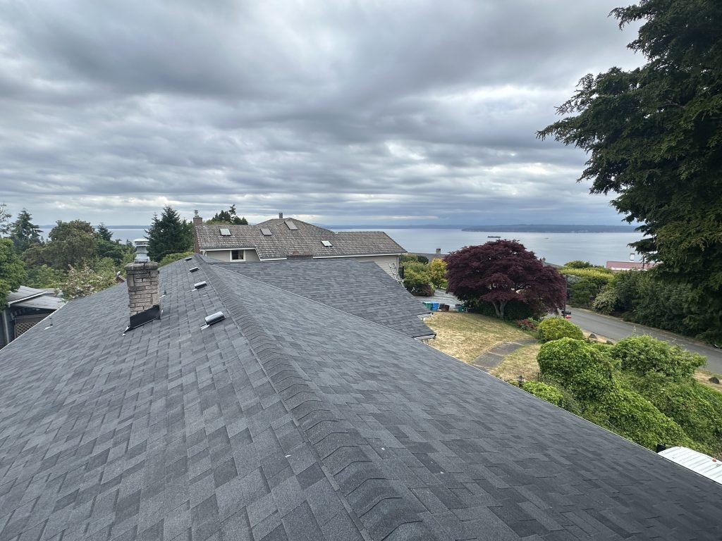 Fresh asphalt shingle roof with scenic ocean backdrop and cloudy sky