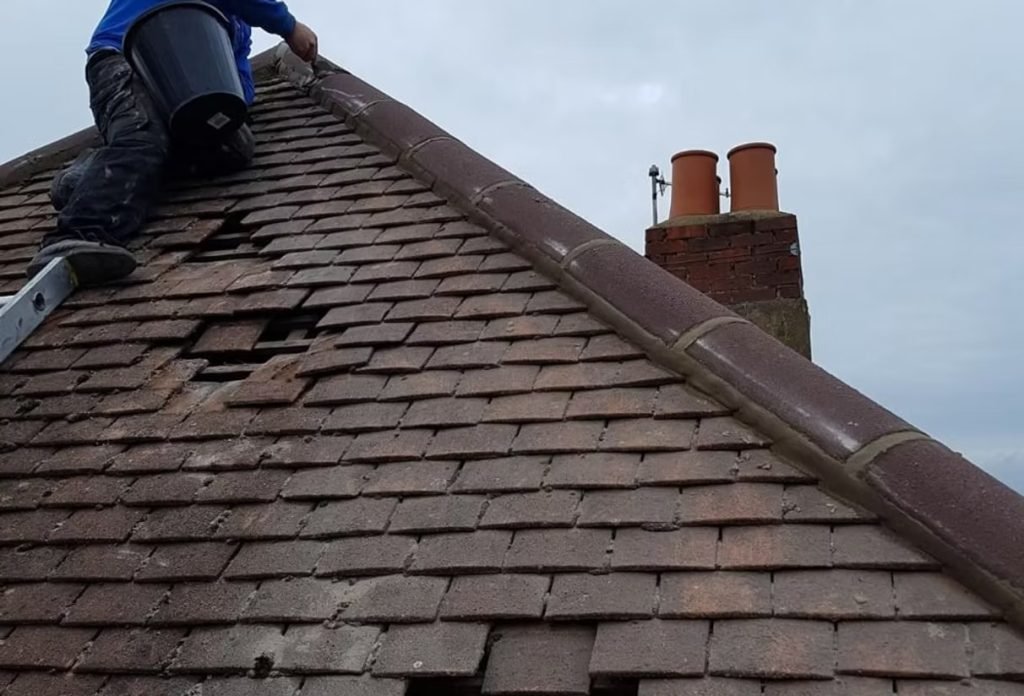 Roofer repairing damaged roof tiles near chimney