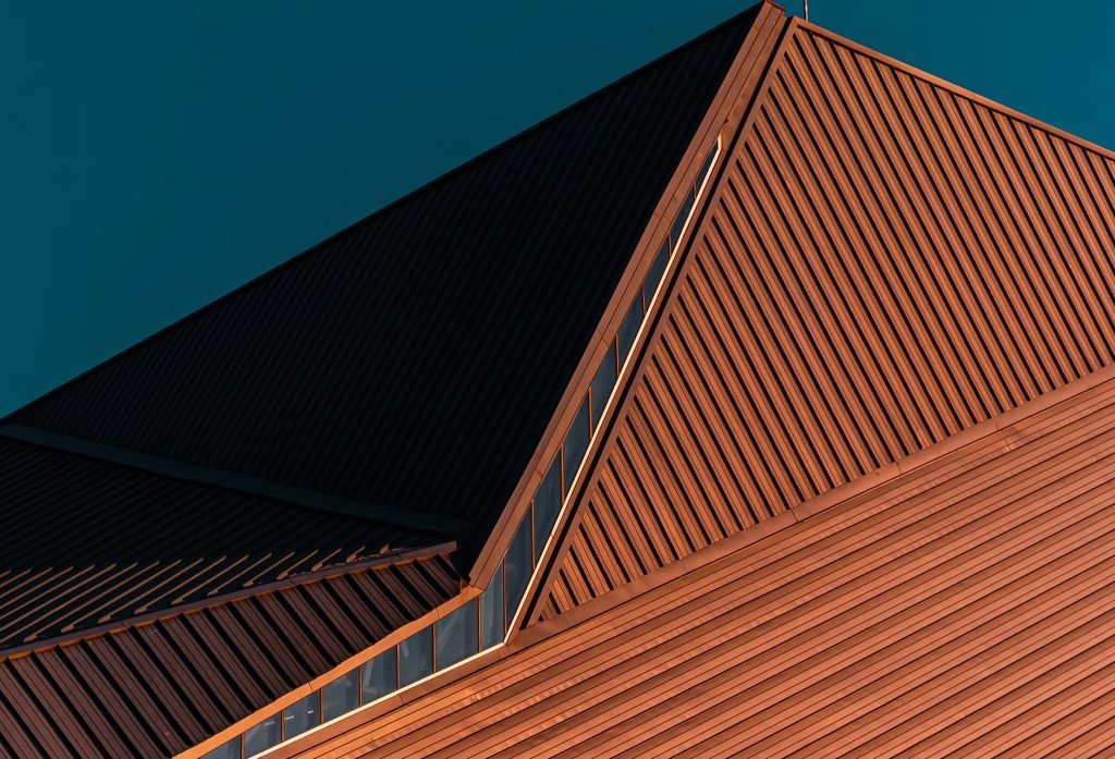 Modern metal roof with sharp angles and large skylights under clear sky