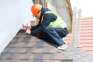 Roofer builder worker dismantling roof shingles