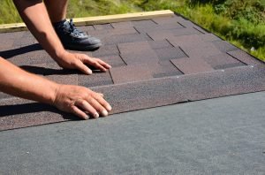 Roofing contractor lay asphalt shingles tiles on house rooftop