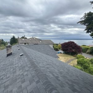 Fresh asphalt shingle roof with scenic ocean backdrop and cloudy sky