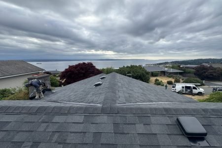Roof replacement in progress with ocean view and cloudy sky