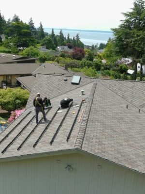 Roofers installing mounting rails for solar panels on asphalt shingle roof